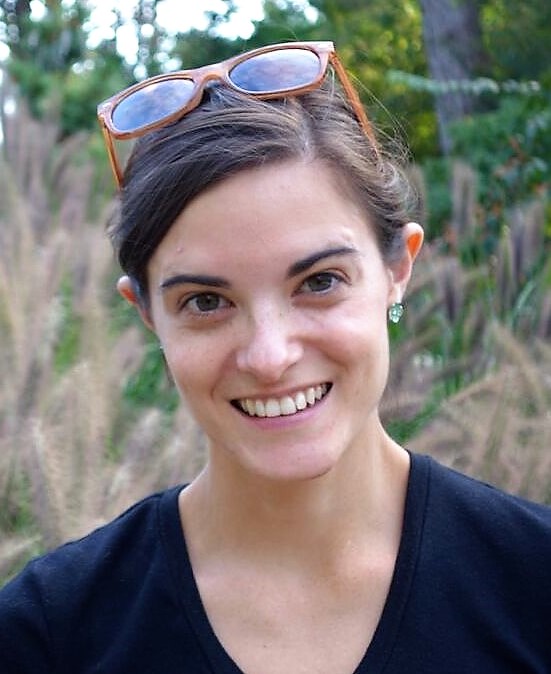 Corlett Wood outside with sunglasses on her head smiling at the camera